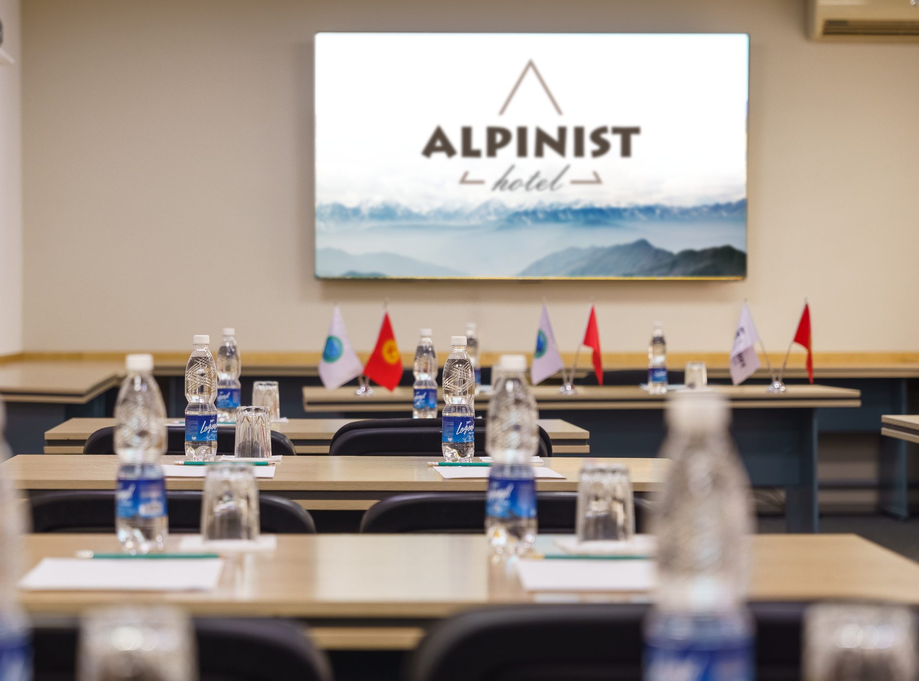 Конференц-зал: столы, флаги и большой экран с логотипом Alpinist